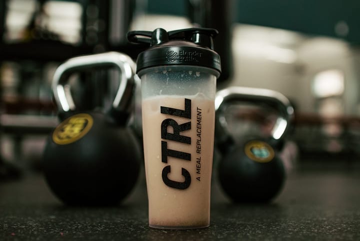 Whey protein shake amidst kettlebells