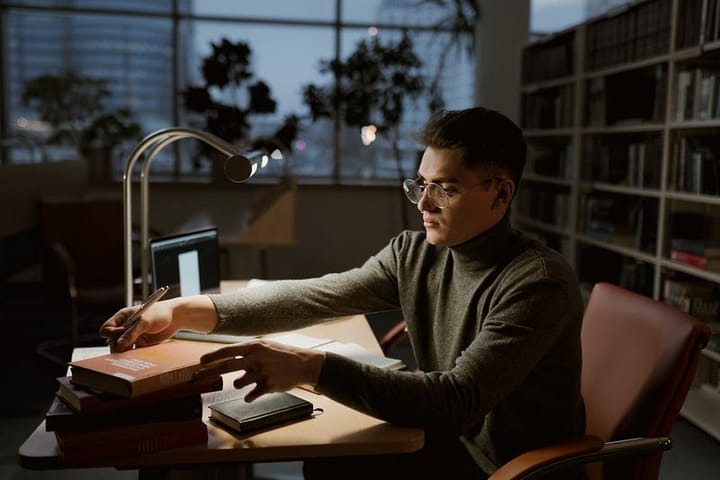A spectacled young man at his work desk